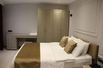 a bedroom with a bed with white sheets and gold pillows at Eyüp Sultan Palace Hotel in Istanbul