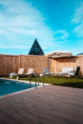 a pool with chairs and an umbrella next to a fence at MY RESORT PRİVE in Sapanca