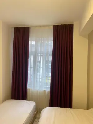 a bedroom with two beds and a window with red curtains at YENİkapı hotel in Istanbul