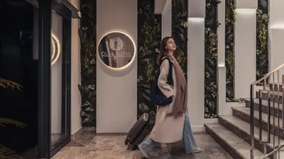 a woman walking down the stairs with a suitcase at Olea Suites Otel in Gemlik