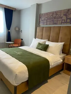 a bedroom with a large bed with a headboard at Gardenmode Airport Hotel in Taşoluk