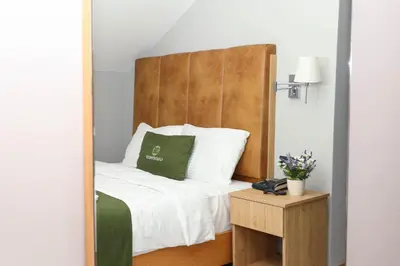 a bedroom with a bed with a wooden headboard at Gardenmode Airport Hotel in Taşoluk