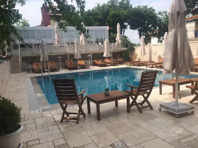 a pool with chairs and umbrellas in front of a hotel at Buyukada Cankaya Hotel in Buyukada