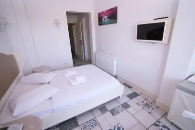 a white room with a bed and a tv at Buyukada Cankaya Hotel in Buyukada