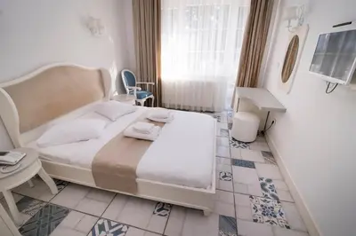 a bedroom with a white bed and a table at Buyukada Cankaya Hotel in Buyukada
