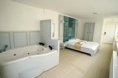 a white bathroom with a tub and a bed at Buyukada Cankaya Hotel in Buyukada