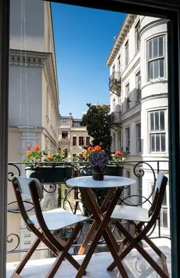 a table and chairs sitting on a balcony with a window at Pera Neuf in Istanbul