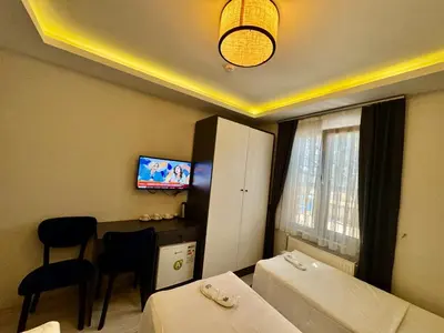 a hotel room with two beds and a table and a television at Aram Edessa Hotel in Istanbul