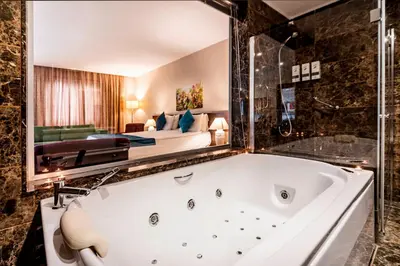 a bath tub in a room with a bedroom at Rox Hotel Istanbul in Istanbul