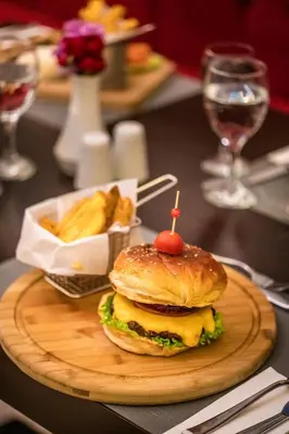 a hamburger and french fries on a wooden plate at Rox Hotel Istanbul in Istanbul