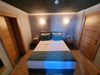 a small room with a bed with blue pillows at City Park Suites City Center Corlu in Corlu