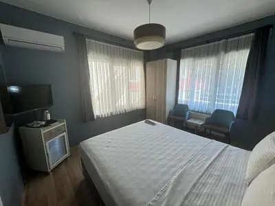 a bedroom with a bed and two chairs and a television at Armoni City Otel Kadıköy in Istanbul