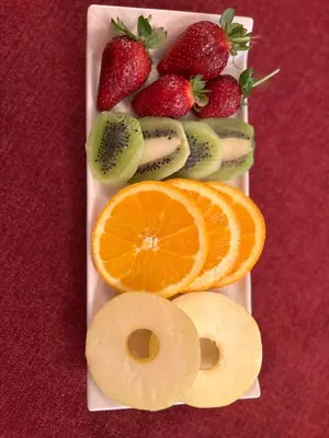a white plate with fruit on a red table at SULTAN SÜLEYMAN APART HOTEL in Istanbul