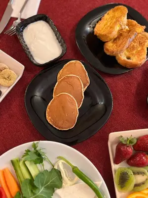 a table with two plates with pancakes and fruit and vegetables at SULTAN SÜLEYMAN APART HOTEL in Istanbul