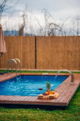 a pool with a glass of wine and a pineapple on a wooden deck at Vital Göl Sapanca Özel Havuzlu Bungalov & Villa in Sapanca