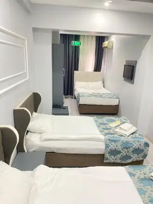 a hotel room with three beds and a tv at Abam Hotel in Istanbul