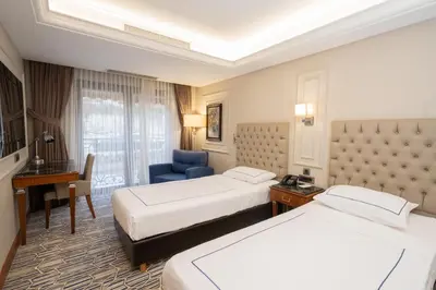 a hotel room with two beds and a desk at Anemon Bursa Otel in Bursa