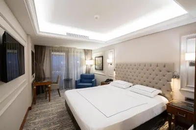 a bedroom with a large white bed and a blue chair at Anemon Bursa Otel in Bursa