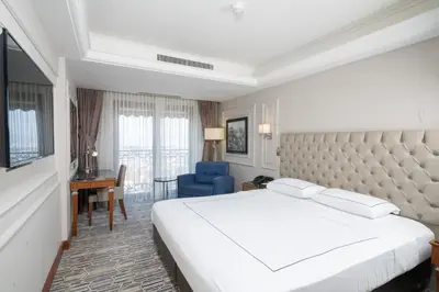 a hotel room with a white bed and a blue chair at Anemon Bursa Otel in Bursa