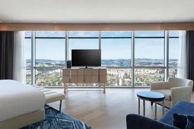 a living room with a tv and large windows at Wyndham Grand Istanbul Levent Hotel & Conference Center in Istanbul