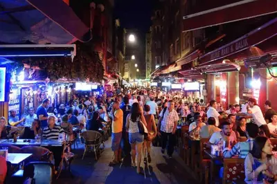a crowd of people walking down a street at night at Central of İstanbul near to so many historic place in Istanbul