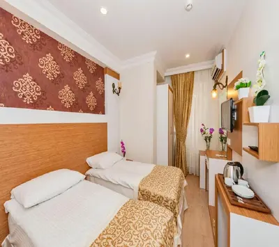 a hotel room with two beds and a desk at Raimond Hotel in Istanbul