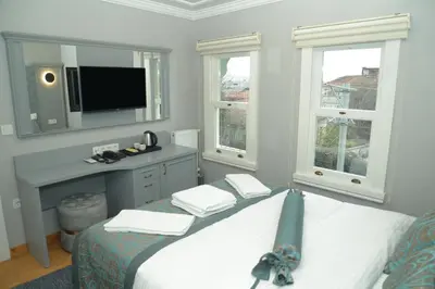 a bedroom with a bed with a tv and windows at CK SULTANAHMET HOTEL in Istanbul