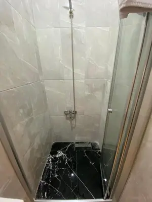 a shower with a glass door with a black marble floor at BEYOĞLU in Istanbul