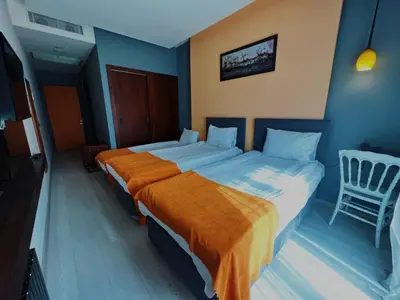 a bedroom with two beds and a chair at N&D&D Hotel in Nilüfer