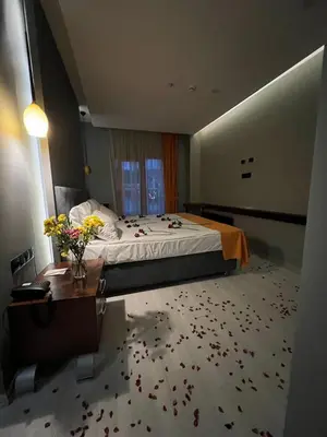 a bedroom with a bed and a table with flowers on the floor at N&D&D Hotel in Nilüfer