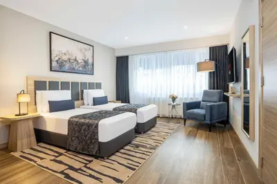 a hotel room with two beds and a chair at The Capri Hotel Osmanbey in Istanbul