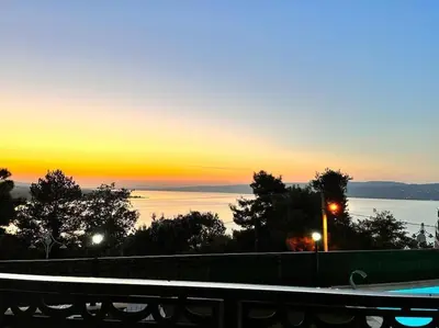 a sunset over the water with a fence and trees at White Home Sapanca in Sapanca
