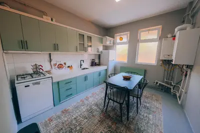 a kitchen with green cabinets and a table with chairs at Alphan House in Sapanca
