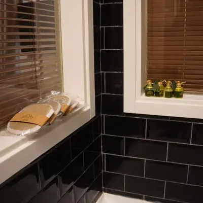 a black tiled bathroom with towels on a shelf at GALATA KULESİ yakınında geniş 3+1 tarihi daire in Istanbul