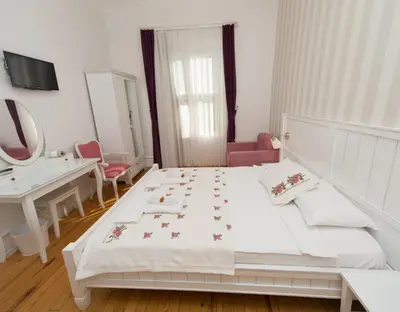 a bedroom with a white bed and a sink and a mirror at Cenar Konak Butik Hotel in Buyukada