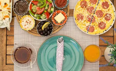a table with plates of food and a pizza at Cenar Konak Butik Hotel in Buyukada