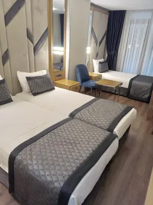 a hotel room with two beds and a chair at Sultanahmet Newport Hotel in Istanbul