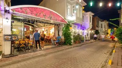 a street with people standing outside a restaurant at night at Rose Apartments in Istanbul