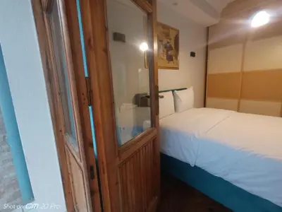 a small bedroom with a bed and a wooden door at Buyukada Cinar Hotel in Buyukada