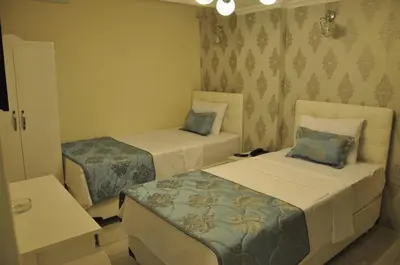 a bedroom with two beds and a table at Hotel Iscen in Mustafakemalpaşa