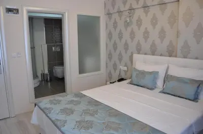 a bedroom with a large bed with blue pillows at Hotel Iscen in Mustafakemalpaşa