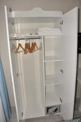 an open white refrigerator with hangers and wooden hoons at Hotel Iscen in Mustafakemalpaşa