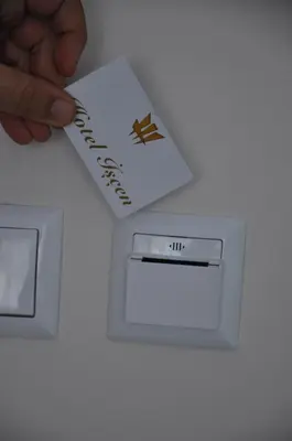 a hand holding a piece of paper next to an electrical outlet at Hotel Iscen in Mustafakemalpaşa