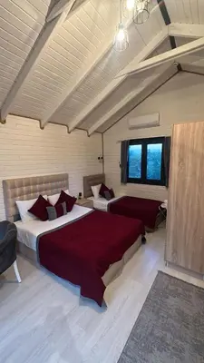 a bedroom with two beds with red sheets and windows at BungalovCity in Sapanca