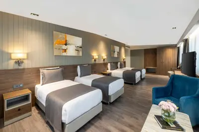 a hotel room with three beds and a couch and a tv at Ezkar Bathonea Art İstanbul Hotel in Avcılar