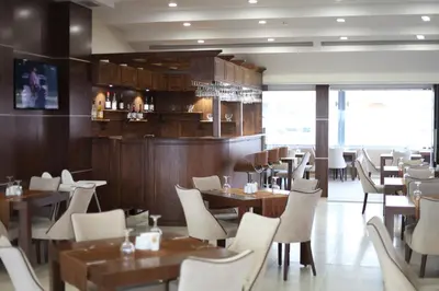 a restaurant with wooden tables and white chairs at Gorukle Oruc Hotel in Bursa