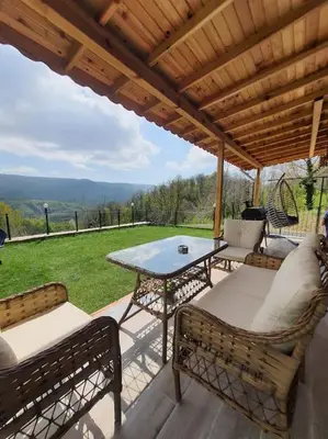 a patio with a table and chairs under a wooden roof at Eviniz rahatlığında, eşsiz doğa manzaralı dağ evi in Gölcük