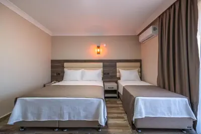 two beds in a hotel room with a window at Avsa Artemis Hotel in Avsa Adasi