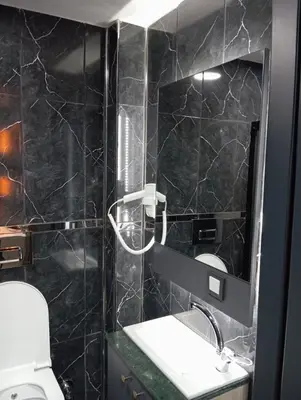 a black tiled bathroom with a toilet and a mirror at Bonita Boutique in Istanbul