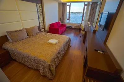 a bedroom with a bed and a red chair in a room at Sea Garden Otel in Darıca